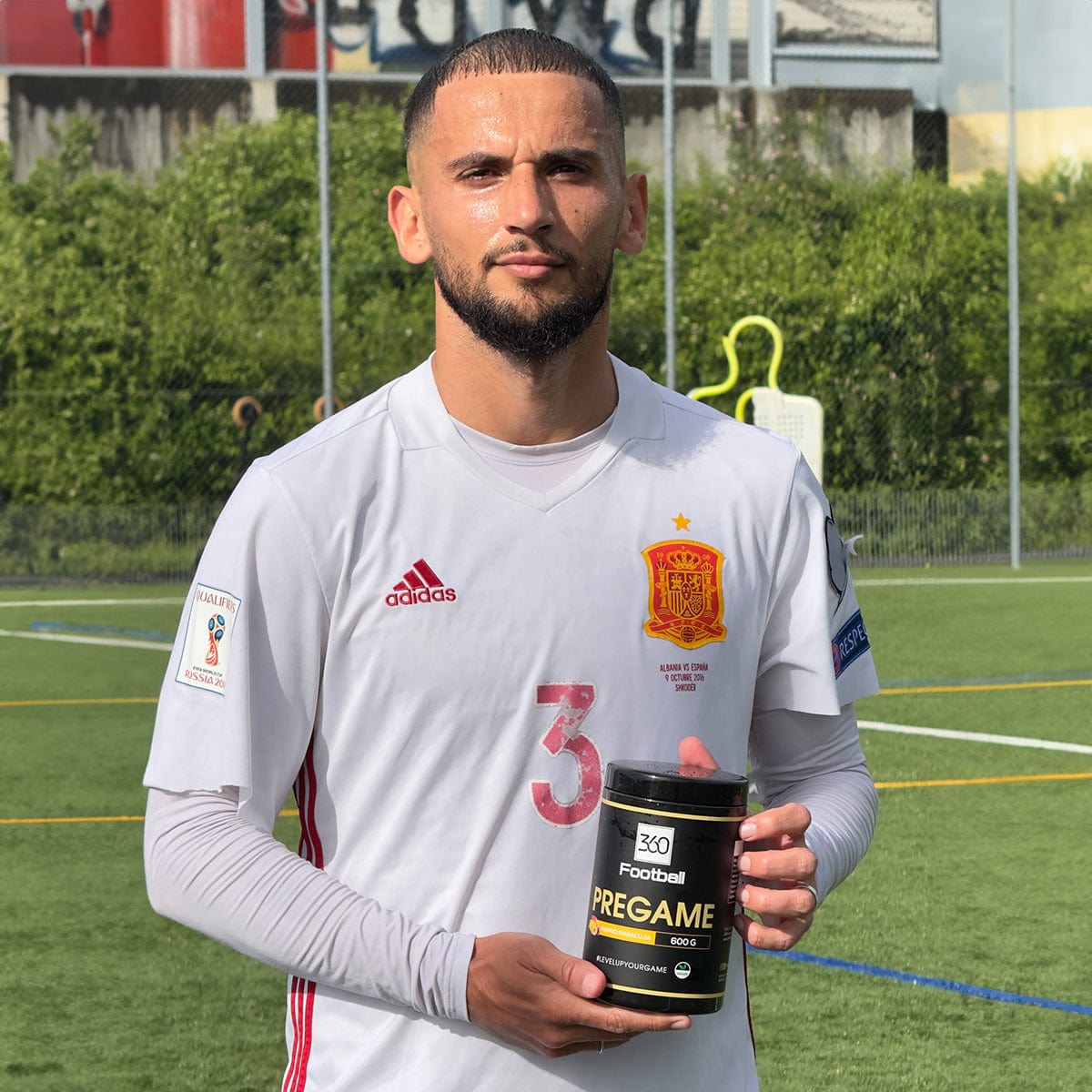 Naser Aliji der albanischen Nationalmannschaft hält einen Pregame360 Mango Maracuja in der Hand auf einem Fussballplatz.