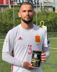 Naser Aliji der albanischen Nationalmannschaft hält einen Pregame360 Mango Maracuja in der Hand auf einem Fussballplatz.