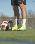 Der 360Football Shaker steht neben einem Fussballer und Ball auf einem Kunstrasen