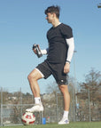 Ein Fussballer steht mit einem Shaker und Creatine360 auf dem Fussballplatz