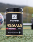 Pregame360 Mixed Berries steht auf einem Fussballplatz, neben einem Ball und einer Kurzhantel.